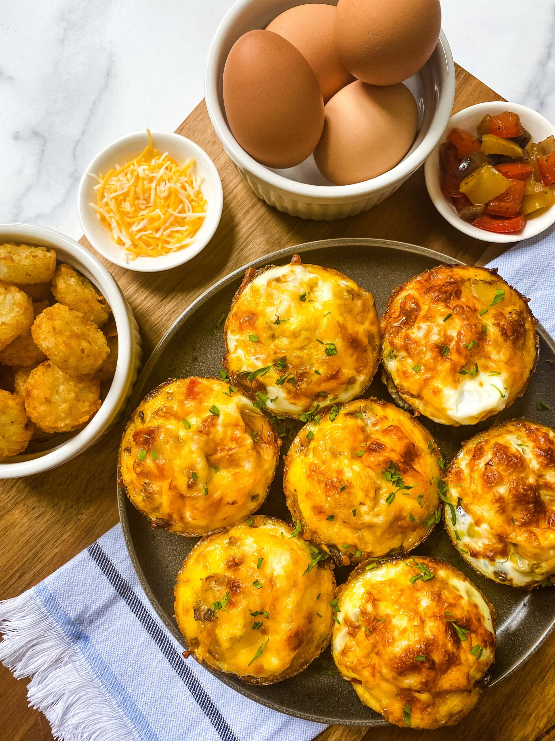 Healthy Egg Muffins With Hash Browns with side dishes of eggs, shredded cheese, cooked onion and bell pepper, and hash browns. Cooking With Fudge