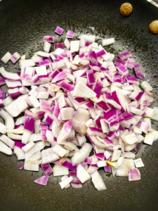 A frying pan with diced red onion. Cooking With Fudge